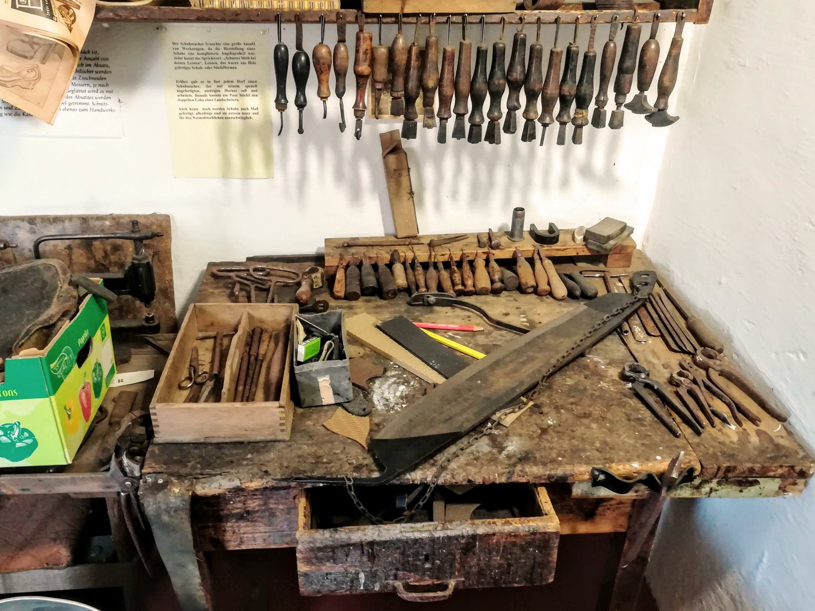 A brown leather lace-up boot with a wooden stretcher inserted on a cobbler's bench